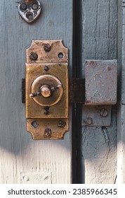 An old gilded brass lock, attached to an old wooden door.