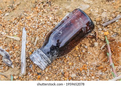 An old glass bottle of medicinal syrup set on gritty ground is perfect for backgrounds, illustrations and wallpapers.