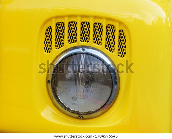 Old glass headlight of\
a yellow truck