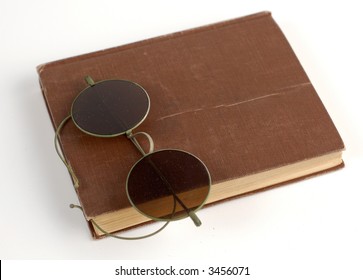 Old glasses and a book on white.