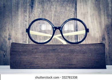 old glasses on old & thick book, wood background + vintage filter - Powered by Shutterstock