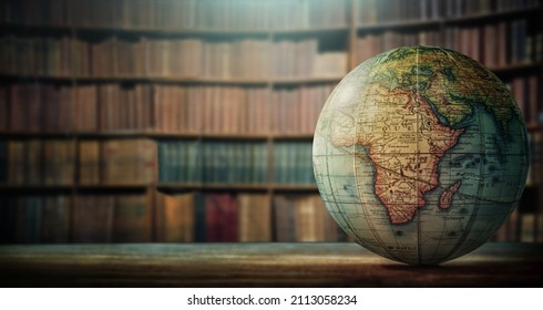 An old globe with Africa on the table against the background of bookcases. Concept on the topic of history, science, culture, education. 