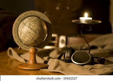 An old globe in a scene with a pair of flying goggles and a candle