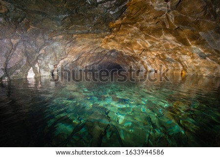Old gold ore mine underground tunnel flooded with blue water