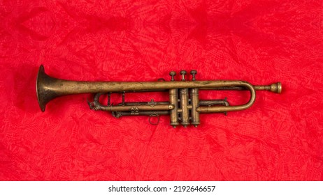 Old Golden Trumpet On Shiny Red Fabric Isolated.