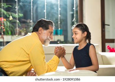 Old grandfather and little granddaughter arm wrestling playing together 