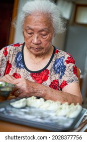 An Old Grandmother In A Chinese Family Is Making Dumplings