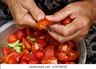 Old grandmother is preparing salad closeup. Old wrinkled hands of grandmother chop vegetables on summer salad. Grandmother prepares food for grandchildren close-up. Grandma cuts tomatoes - Powered by Shutterstock