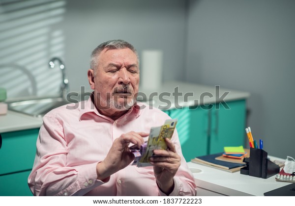 The old\
grandpa counting money in the doctors\
office.
