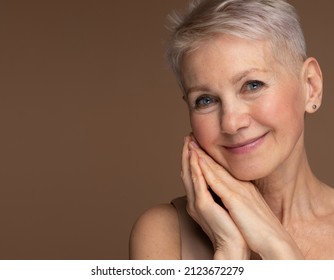 Old Granny. Close Up Portrait Of Beautiful Older Woman Smiling. Isolated Over Brown Background.