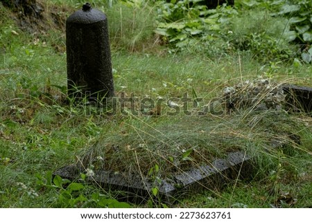 Old grave mark in the middle of a cemetry with green grass