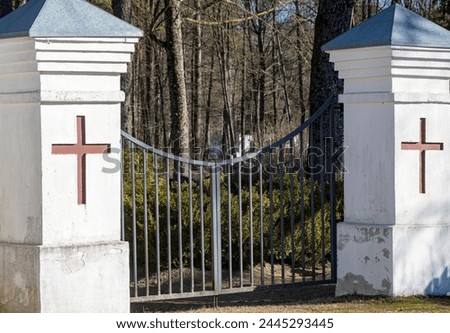Old Graveyard Gate. Old metal and weathered gate of a graveyard with massive columns and Christian crosses