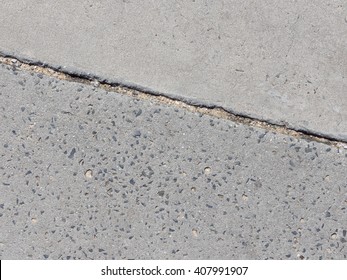 Old gray concrete surface with depressed gravel and the gray concrete decorative surface and expansion joint between them on the track to the street