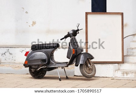 An old gray-black retro scooter is parked on a Zanzibar street near a frame or table. A place to write text.