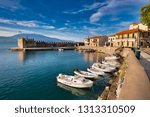 Old Greek port Nafpaktos with ancient castle walls an background and fishing boats at foreground. Epic lilac colored sunrise sky over sea scenery. Nafpaktos is famous travel destination in Greece. 