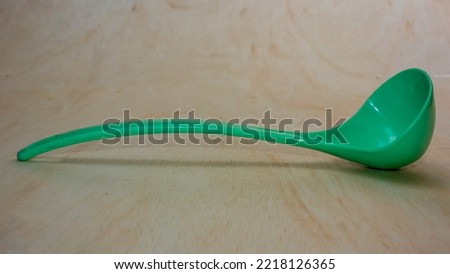 Old green plastic spoon placed on a wooden table