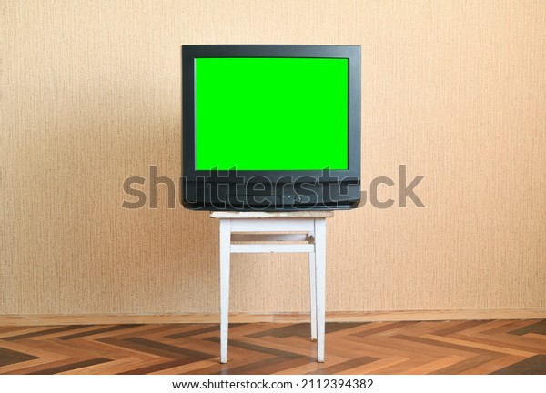 Old green screen TV on an old chair, old\
house design in 1980s and 1990s\
style.