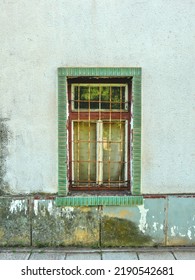 An Old Green Window With Cracked Paint In The Middle Of A Wall Worn By Time.