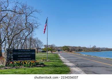 Old Greenwich, CT, USA-May 2022: View of the entrance of Greenwich Point Park or Tods Point with large entrance sign next to road with American flag against a blue sky