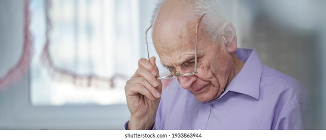 Old Grey Haired Man Wearing Eyeglasses Writes Or Reads Couching Head Over Table