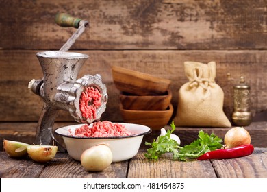 old grinder with minced meat and vegetables on wooden table