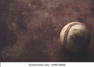 Old Grunge Baseball Ball On Brown Texture Background With Copy Space, Blurred Backdrop With Shallow Depth Of Field.