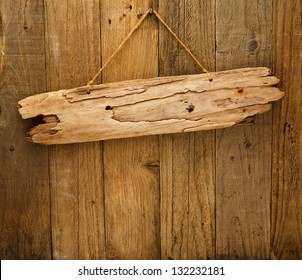 old grungy antique wooden plank of driftwood on string hung on timber plank wall