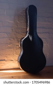 An Old Guitar Case Resting Against A Brick Wall At Sunrise