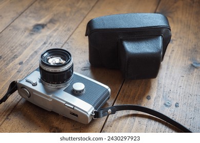 An old half-frame camera on top of a wooden table.