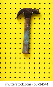 Old Hammer With Paint Marks Hangs From Metal Hook On Pegboard