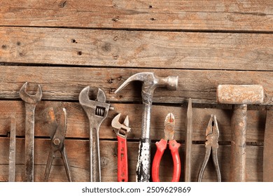 Old hand tools on a wooden surface, top view. Adjustable wrench, hammer, sledgehammer, tin snips and pliers. Tools for repair and construction. Wooden floor and tools - Powered by Shutterstock