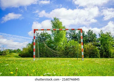 Old handball goal with a broken net on a green lawn in the summer with a blue sky - Shutterstock ID 2160746845