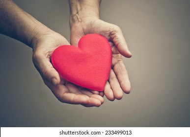 Old Hands Of The Elderly Giving A Red Heart