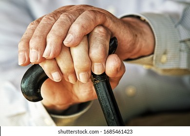 Old hands resting on a walking stick