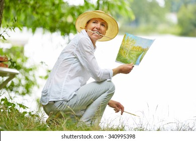 Old Happy Woman Painting A Picture With Brush In Nature