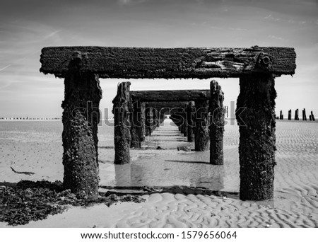 Old Harbour on the Beach of Wangerooge Island. Landing stage, rotten pier in National Park and World Heritage “Wattenmeer“ North Sea Ostfriesland Germany. Weathered wooden structure Lack and white.