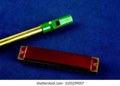 Old harmonica and tin whistle on a blue background