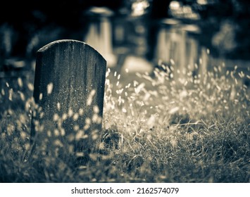 Old Headstone Covered In Grass In A Graveyard