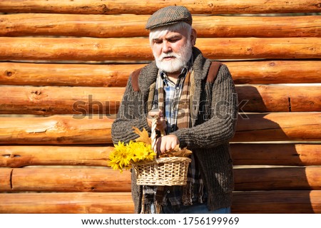 Old hipster man with flowers. Portrait of aged man with beard. Happy man with beard and mustache hold basket of flowers. Outdoor portrait. Wooden background