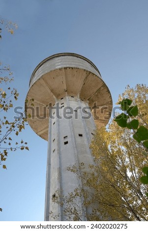 Old historic concrete water tower on the premises of the historic steelworks in Ostrowiec Swietokrzyski.A tall concrete water tower on a sunny autumn day against a blue sky without clouds. 