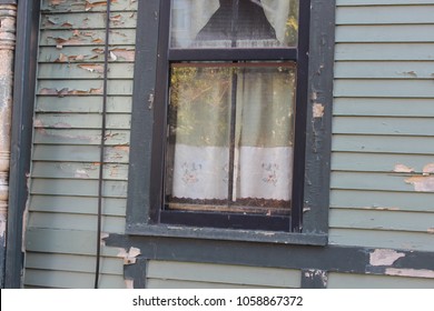 Old historic wooden house in disrepair with faded peeling and chipped paint and rotted wood