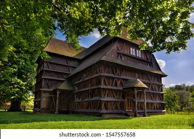 Old historical wooden church behind trees on fresh green grass in Hronsek, part of wooden churches of carpathian arc and UNESCO world heritage - Powered by Shutterstock