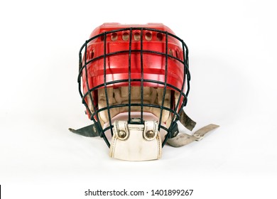 An Old Hockey Helmet Of Red Color With A Protective Iron Mask On A White Background. Front View