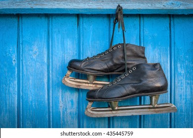 Old Hockey Skates Hanging On A Blue Wooden Wall