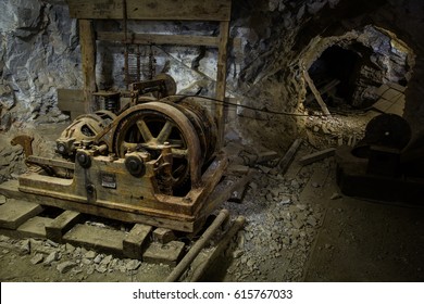 An Old Hoist And Several Other Pieces Of Worn-down Mining Equipment Inside Of An Abandoned Mine In Western Utah. 