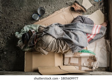 Old homeless man wearing sweater and blanket sleeping on cardboard seeking help because hungry and food beggar from people walking pass on street. Poor man homeless and depression concept. - Shutterstock ID 1805609977