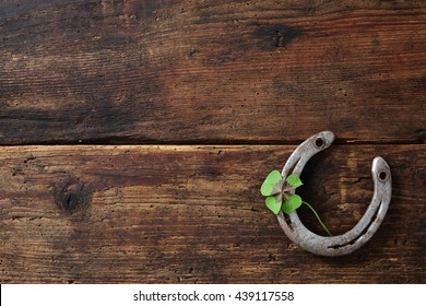 Old horse shoe with clover leaf on rustic wooden background