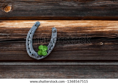 Old horseshoe and four leaf clover on a vintage wooden board. The concept of luck, luck, luck. St. Patricks Day card.
