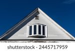 Old house attic bow window and small air vent against clear blue sky in Boston, Massachusetts, USA