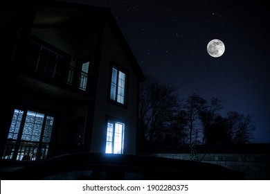 Old House With A Ghost In The Forest At Misty Night Or Night Scene With House Under Moon. Old Mystic Building In Dead Tree Forest.